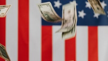 National flag of United States of America on background and dollars falling down